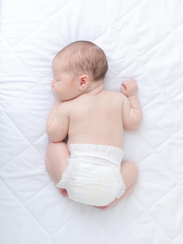 Overhead view of baby curled up on their belly during newborn photos.